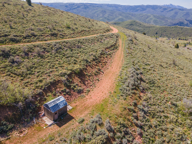 3325 North Oak Cyn Road, Unit 490 Huntsville, UT 84317 - Photo 1 of 25 Unpaved roadway winding through a mountainous landscape with a small wooden structure featuring a metal roof