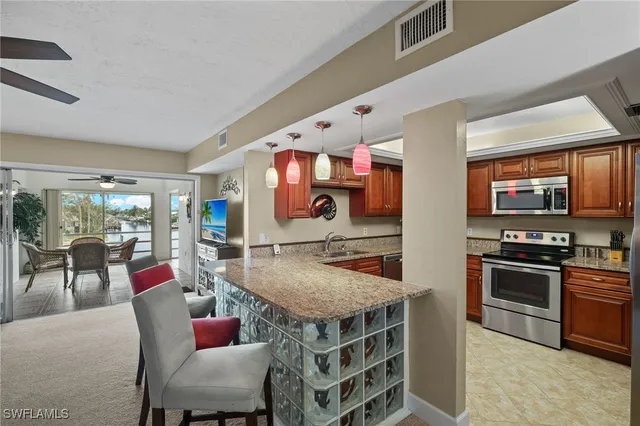 a dining hall with stainless steel appliances granite countertop a stove and a sink