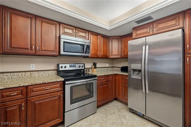 a kitchen with granite countertop a refrigerator stove and microwave