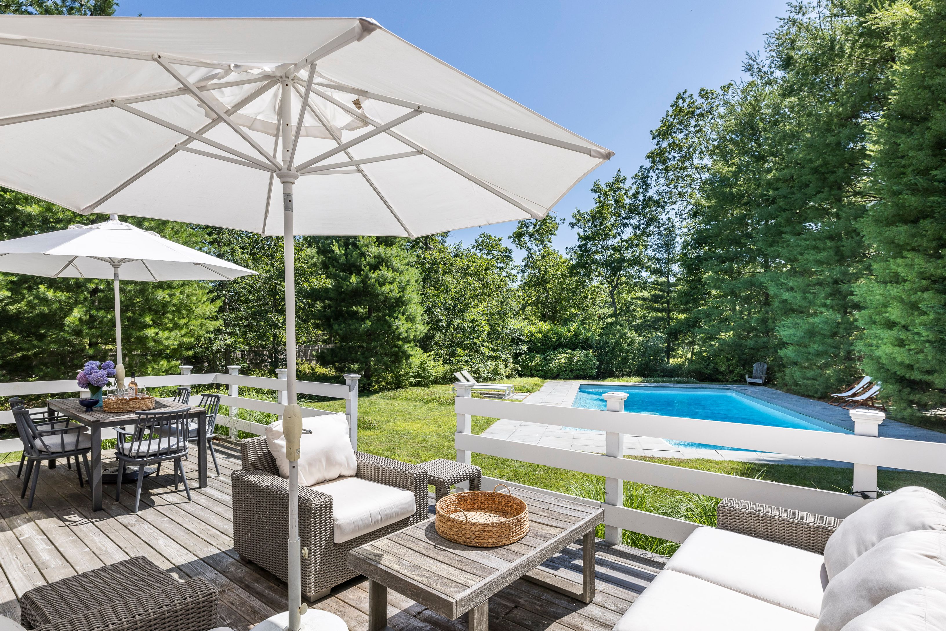 97 Swamp Road East Hampton, NY 11937 - Photo 3 of 28 a patio with a table and chairs under an umbrella