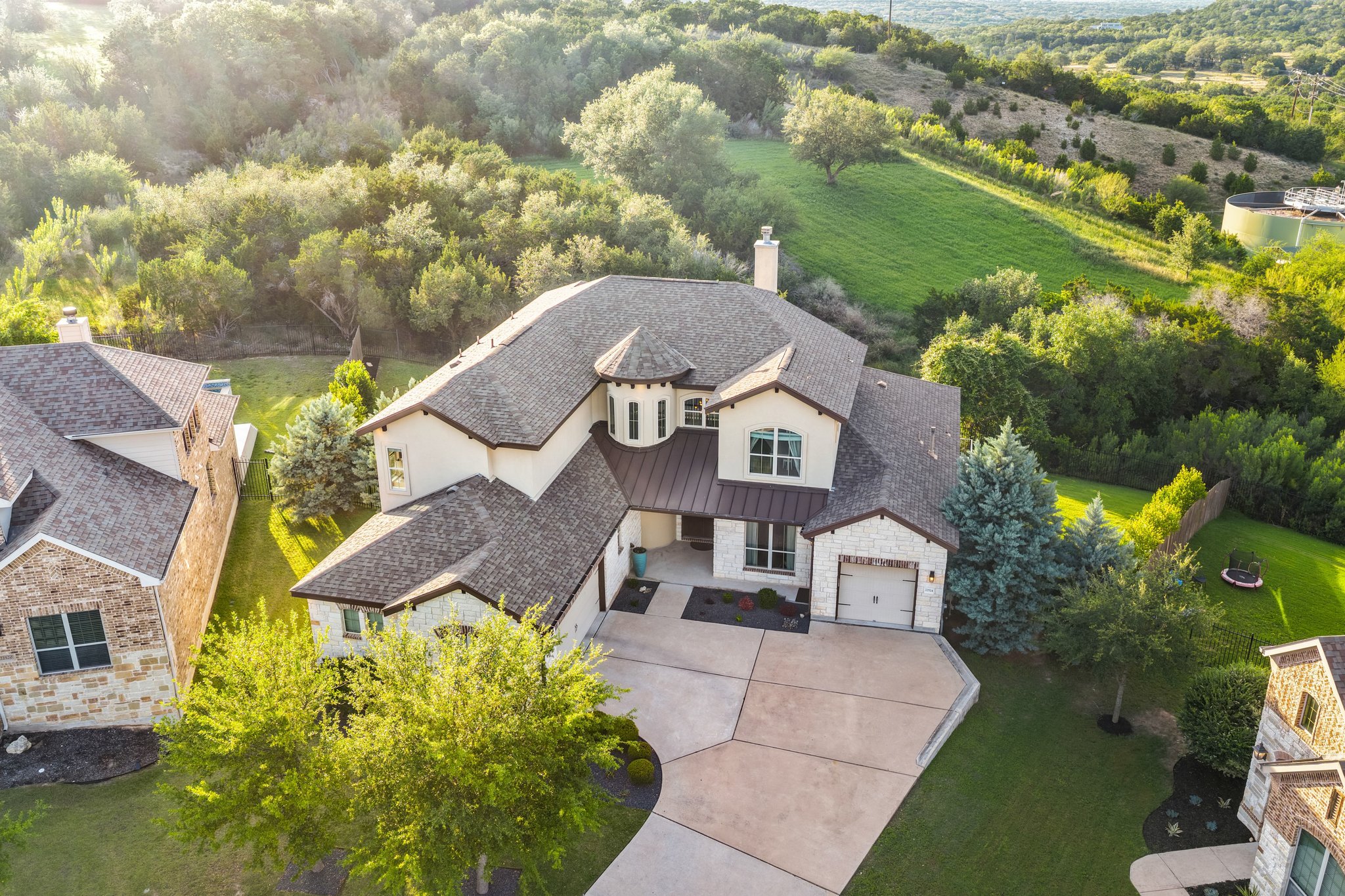 22524 Rock Wren Road Spicewood, TX 78669 - Photo 1 of 40 Exterior featuring a blend of stucco and stone finishes, a multi-gabled roofline, and a prominent turret element