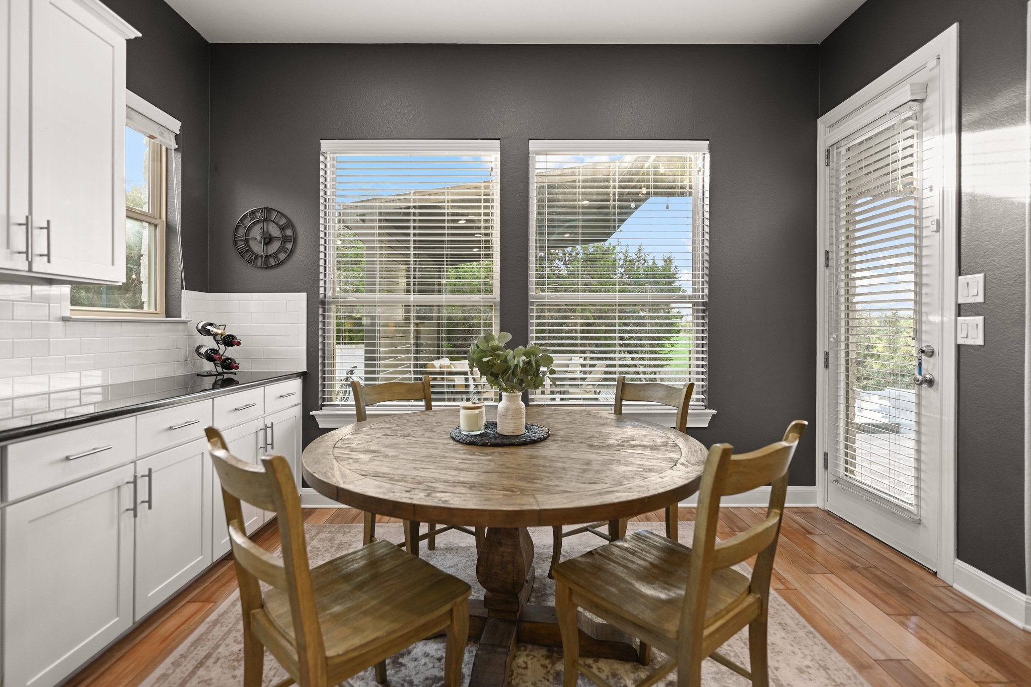 22524 Rock Wren Road Spicewood, TX 78669 - Photo 15 of 40 Dining area with wood-finish flooring, white cabinetry, dark countertops, and a white subway tile backsplash