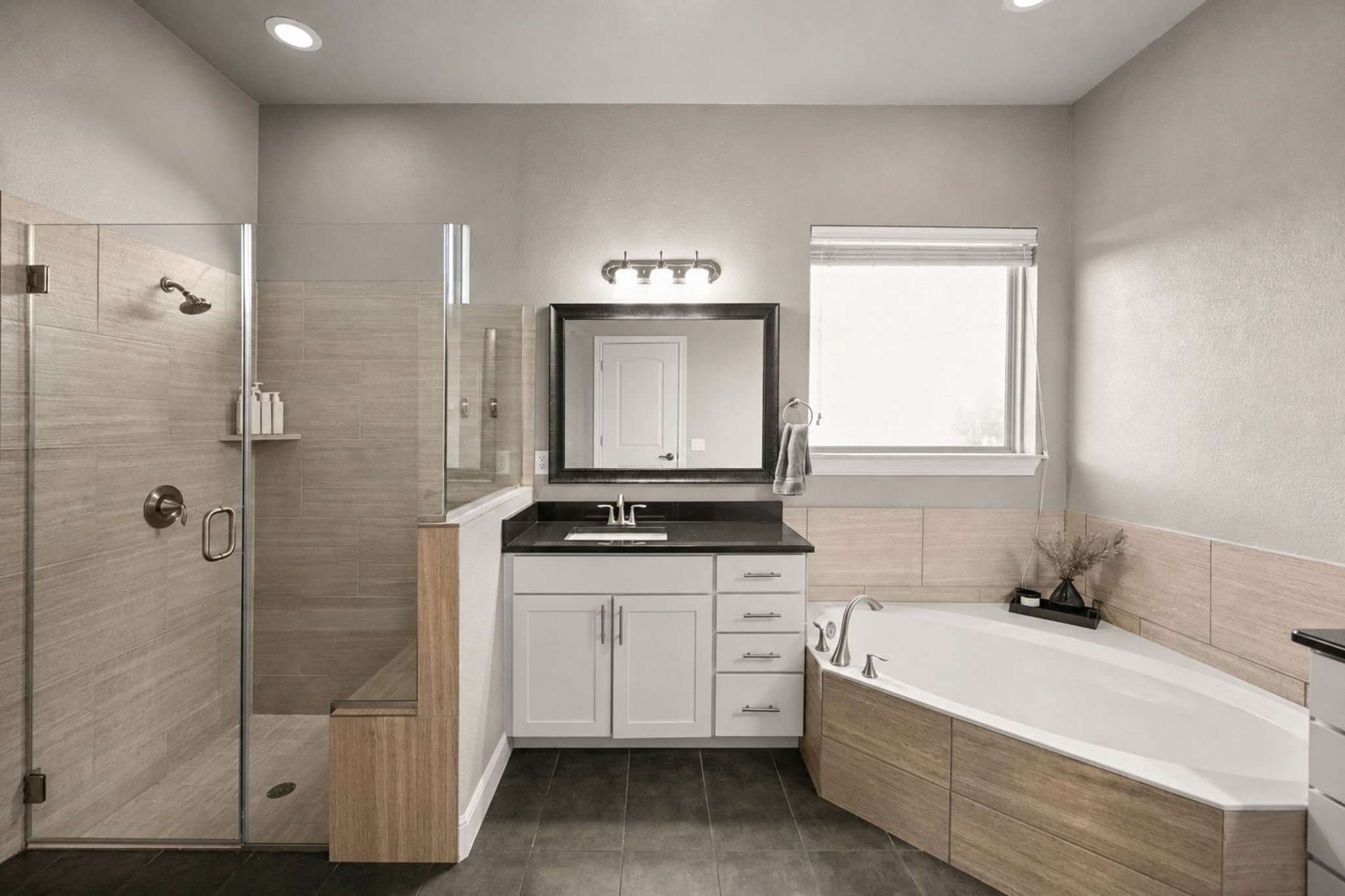 22524 Rock Wren Road Spicewood, TX 78669 - Photo 18 of 40 Bathroom featuring a glass-enclosed shower with a built-in bench, a separate soaking tub with wood-finish paneling, a vanity with white cabinetry and a dark countertop, a rectangular mirror, and dark tile flooring