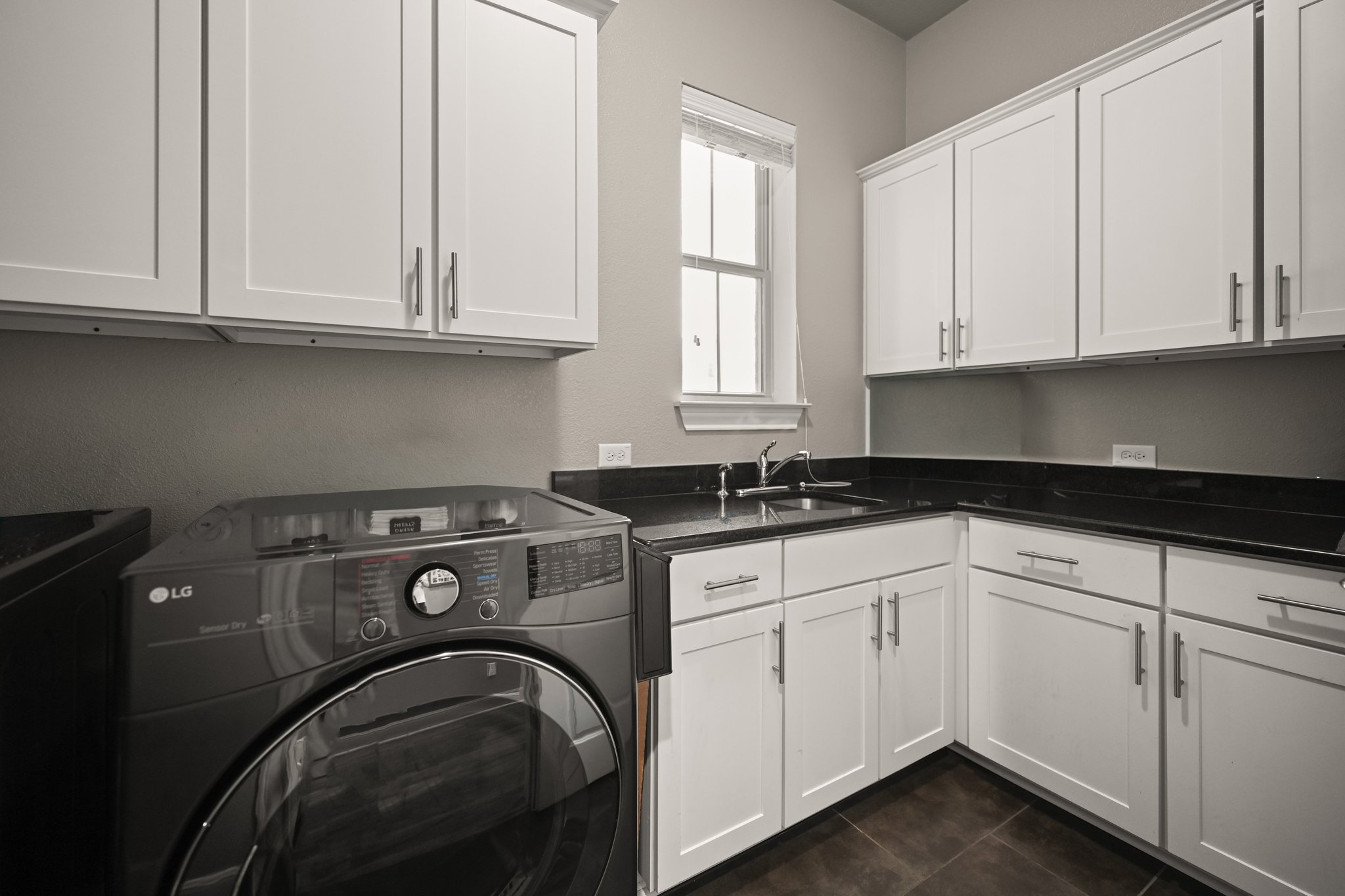 22524 Rock Wren Road Spicewood, TX 78669 - Photo 21 of 40 Dedicated utility space featuring extensive white shaker cabinetry, dark countertops, a stainless steel sink with a chrome faucet, a window for natural light, and dark tile flooring