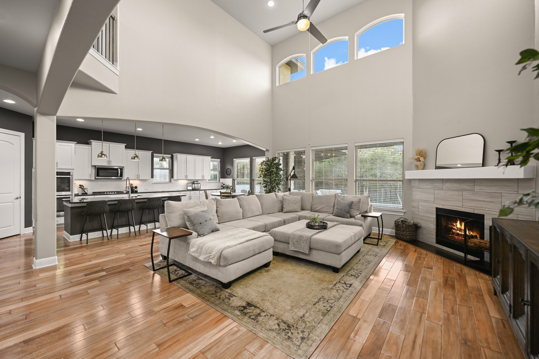 22524 Rock Wren Road Spicewood, TX 78669 - Photo 5 of 40 Spacious living area featuring high ceilings, wood-finish flooring, a contemporary fireplace with a tiled surround, and multiple windows