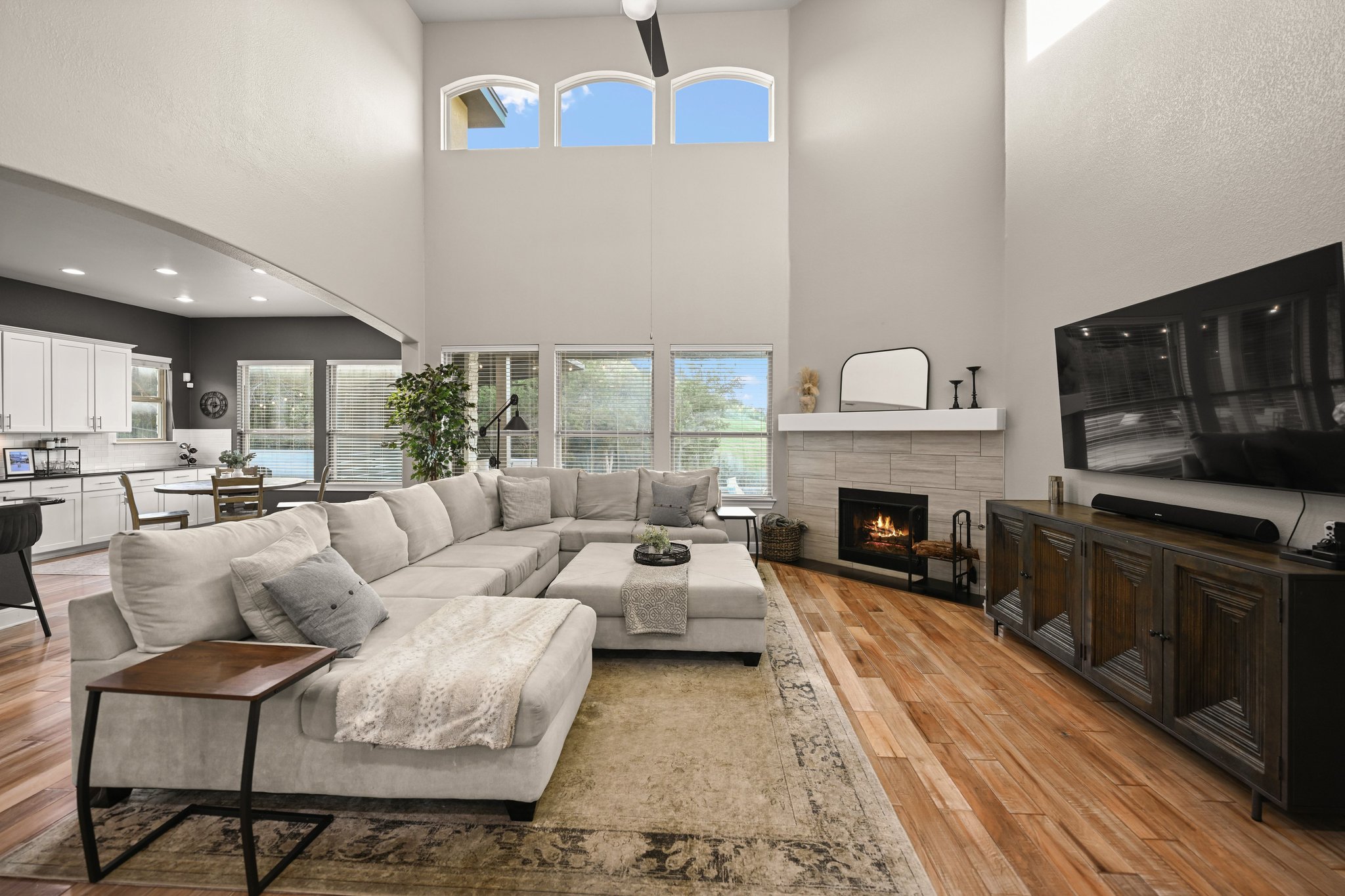 22524 Rock Wren Road Spicewood, TX 78669 - Photo 6 of 40 Two-story living area featuring hardwood flooring, a stone-clad fireplace with a white mantle, and multiple windows