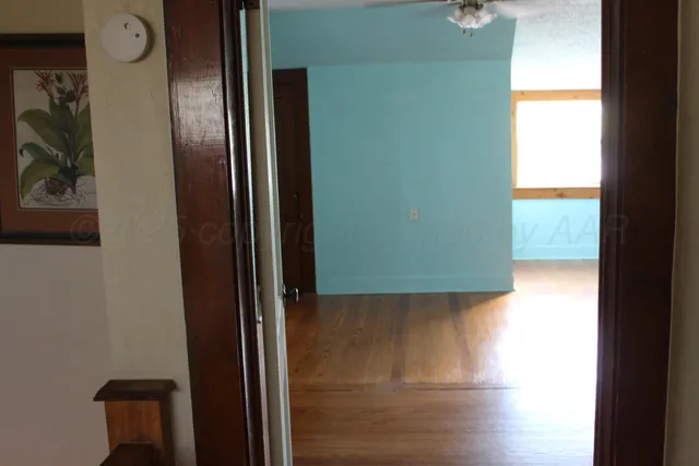 a view of an empty room with wooden floor and closet
