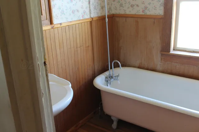 a walk in closet with wooden floor