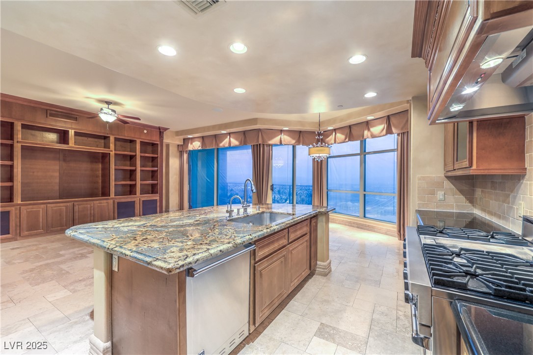 9101 Alta Drive, Unit 1406 Las Vegas, NV 89145 - Photo 14 of 69 Kitchen with brown cabinets, appliances with stainless steel finishes, recessed lighting, light stone counters, and a kitchen island with sink