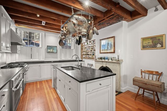 a kitchen that has a sink and a stove with wooden floor