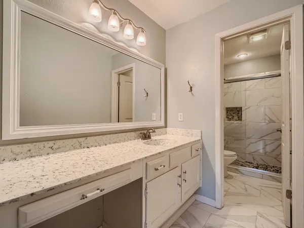 a bathroom with a granite countertop sink mirror and toilet