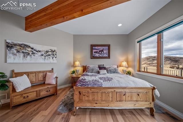 4586 East Best Road Larkspur, CO 80118 - Photo 16 of 50 Bedroom featuring beamed ceiling, wood finished floors, a mountain view, and recessed lighting