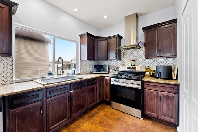 a kitchen with stainless steel appliances granite countertop wooden cabinets stove top oven and sink