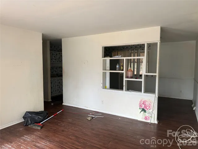 a view of an empty room with wooden floor and windows