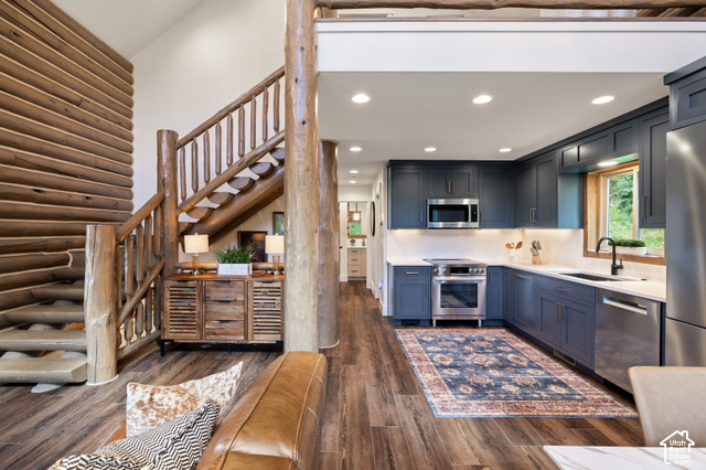 917 West Deep Forest Road Coalville, UT 84017 - Photo 11 of 41 Custom log construction, wood-finish flooring, a full kitchen with dark blue cabinetry, stainless steel appliances, and white countertops