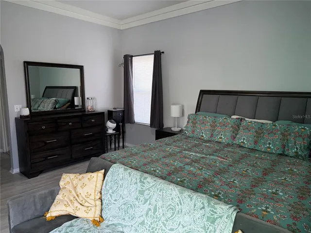 a bedroom with a bed and a flat tv screen on dresser