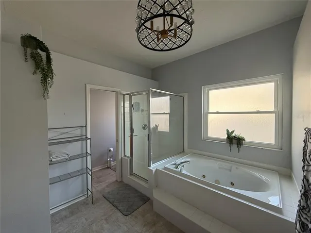 a bathroom with a tub a window and a chandelier