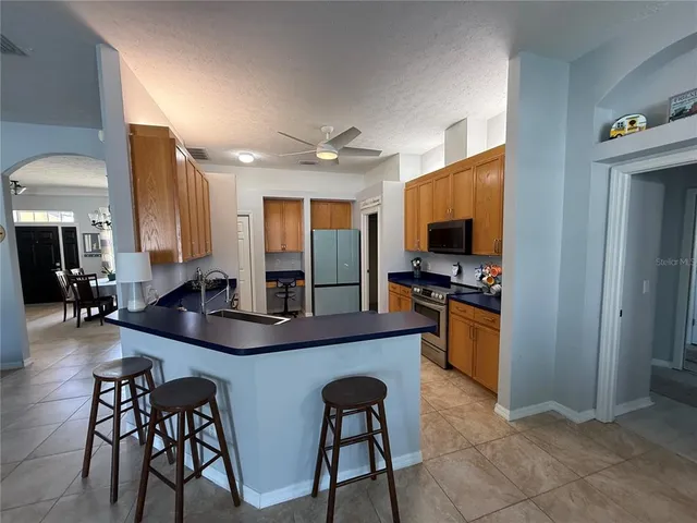 a kitchen with stainless steel appliances granite countertop a stove top oven a sink a dining table and chairs