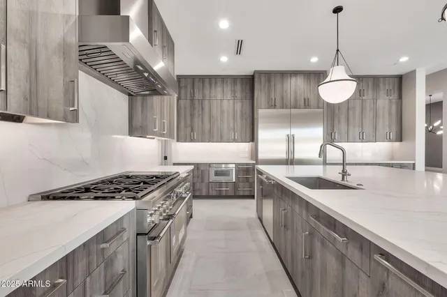 a kitchen with stainless steel appliances granite countertop a refrigerator a sink and wooden cabinets