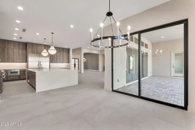 a view of an empty room with chandelier fan and fire place