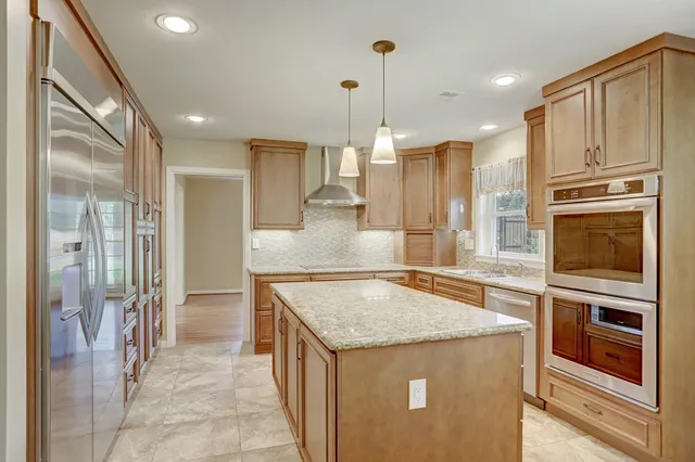 a kitchen with stainless steel appliances granite countertop a refrigerator and a stove top oven