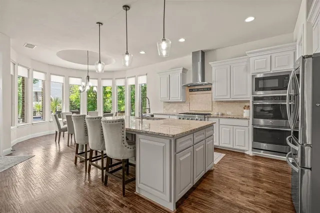 a kitchen with kitchen island granite countertop wooden floors and white appliances