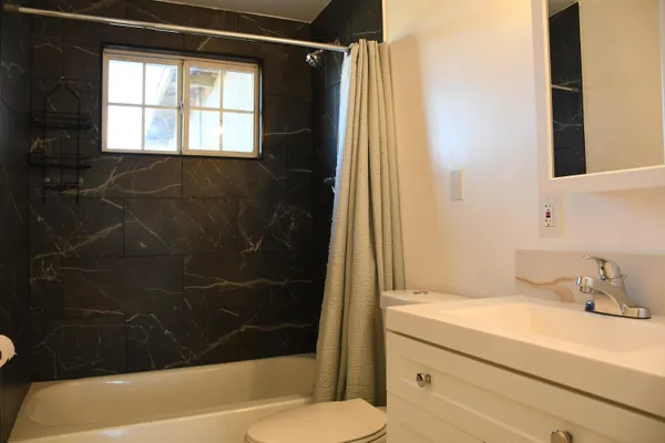 a bathroom with a granite countertop sink toilet and shower