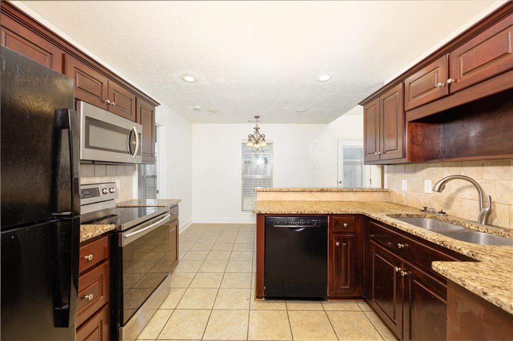 8 Ridgebrook Drive Phenix City, AL 36869 - Photo 10 of 21 Kitchen featuring black appliances, tasteful backsplash, a chandelier, light tile patterned floors, and a peninsula