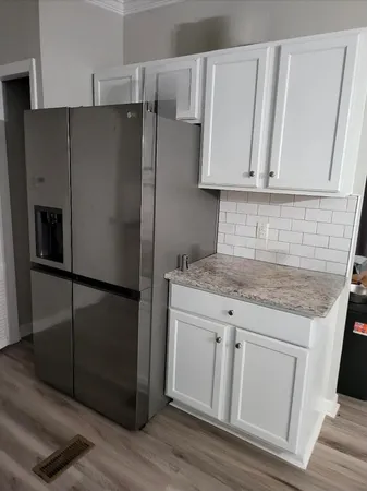 a kitchen with white cabinets and refrigerator