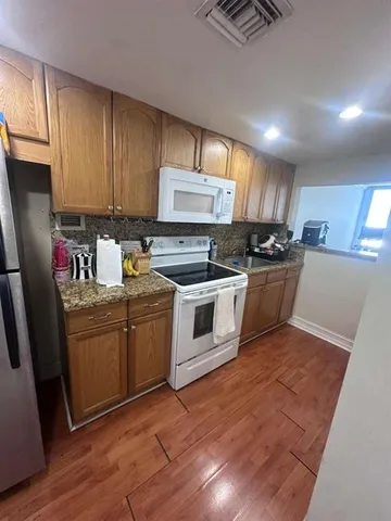 a kitchen with granite countertop a sink cabinets and stainless steel appliances