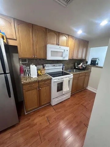 a kitchen with stainless steel appliances granite countertop a stove a sink dishwasher a refrigerator and cabinets with wooden floor