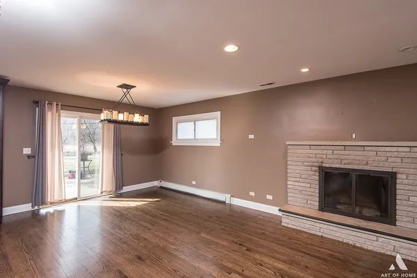 an empty room with wooden floor fireplace and windows