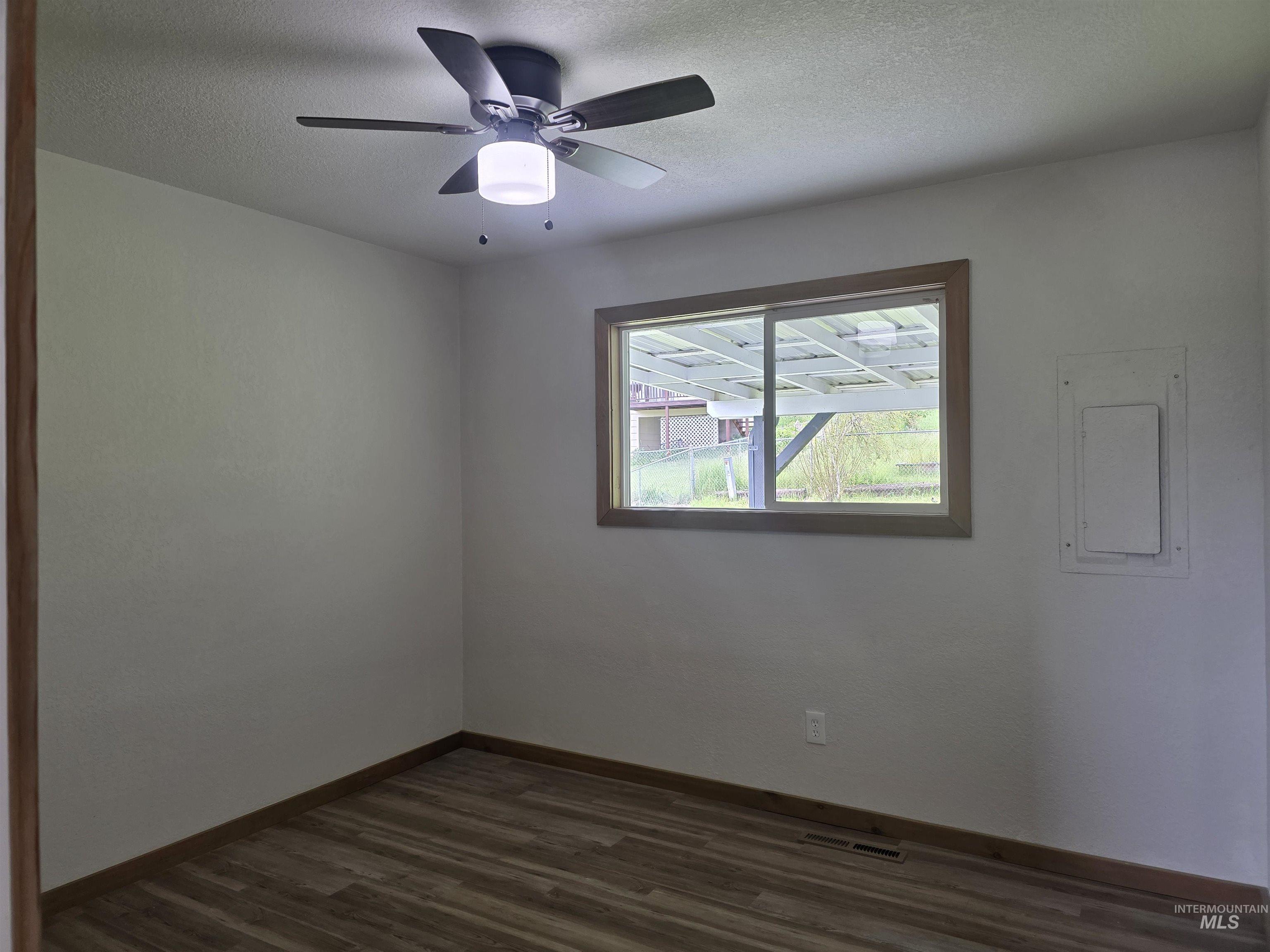 310 Fir Road Kamiah, ID 83536 - Photo 19 of 32 Room featuring wood-finish flooring, a window with wood trim, a ceiling fan with integrated lighting, and neutral wall paint