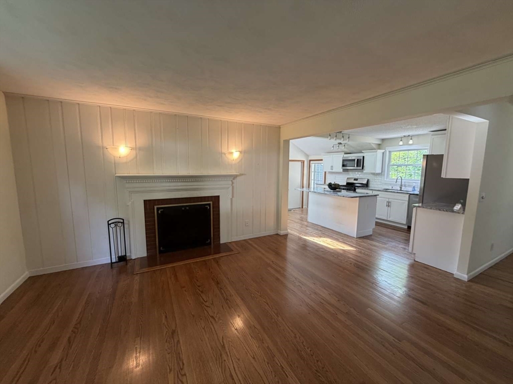74 Birch Road Longmeadow, MA 01106 - Photo 9 of 38 a view of a living room a kitchen with wooden floor and a fireplace
