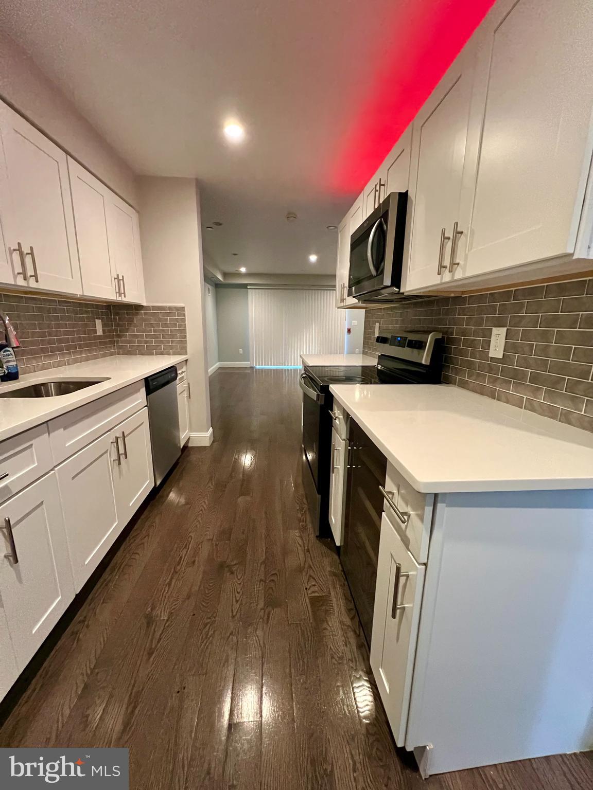 1703 South 22nd Street, Unit 1 Philadelphia, PA 19145 - Photo 9 of 27 a kitchen with stainless steel appliances granite countertop a sink a stove and a wooden floors