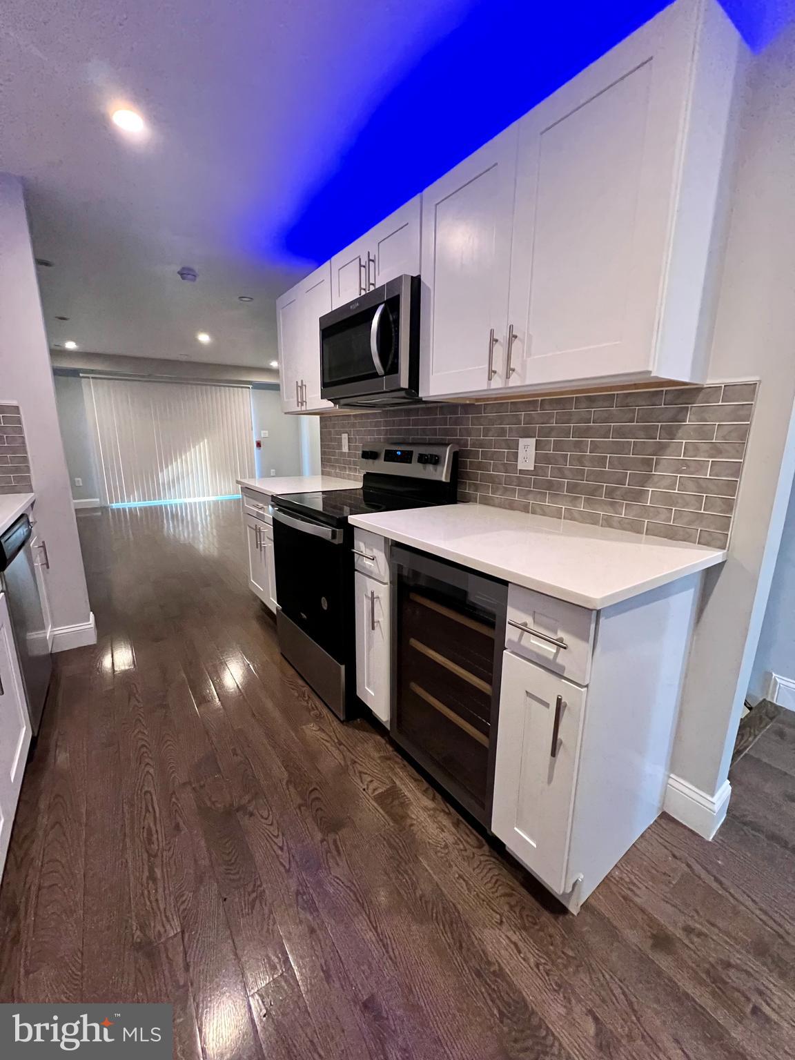 1703 South 22nd Street, Unit 1 Philadelphia, PA 19145 - Photo 10 of 27 a kitchen with stainless steel appliances a stove a microwave and a hard wood floor