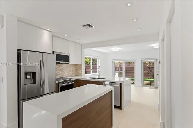 a kitchen with stainless steel appliances granite countertop a refrigerator and a stove top oven