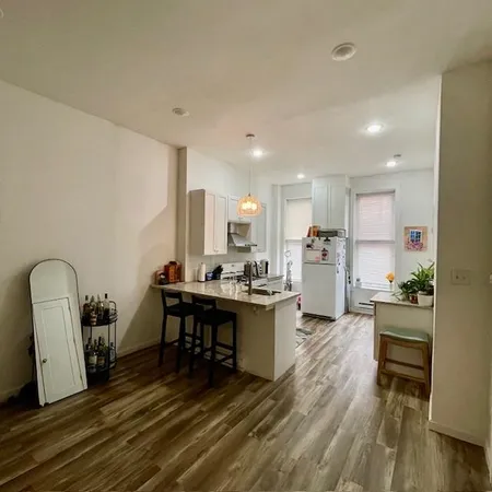 a living room with furniture a wooden floor and kitchen view