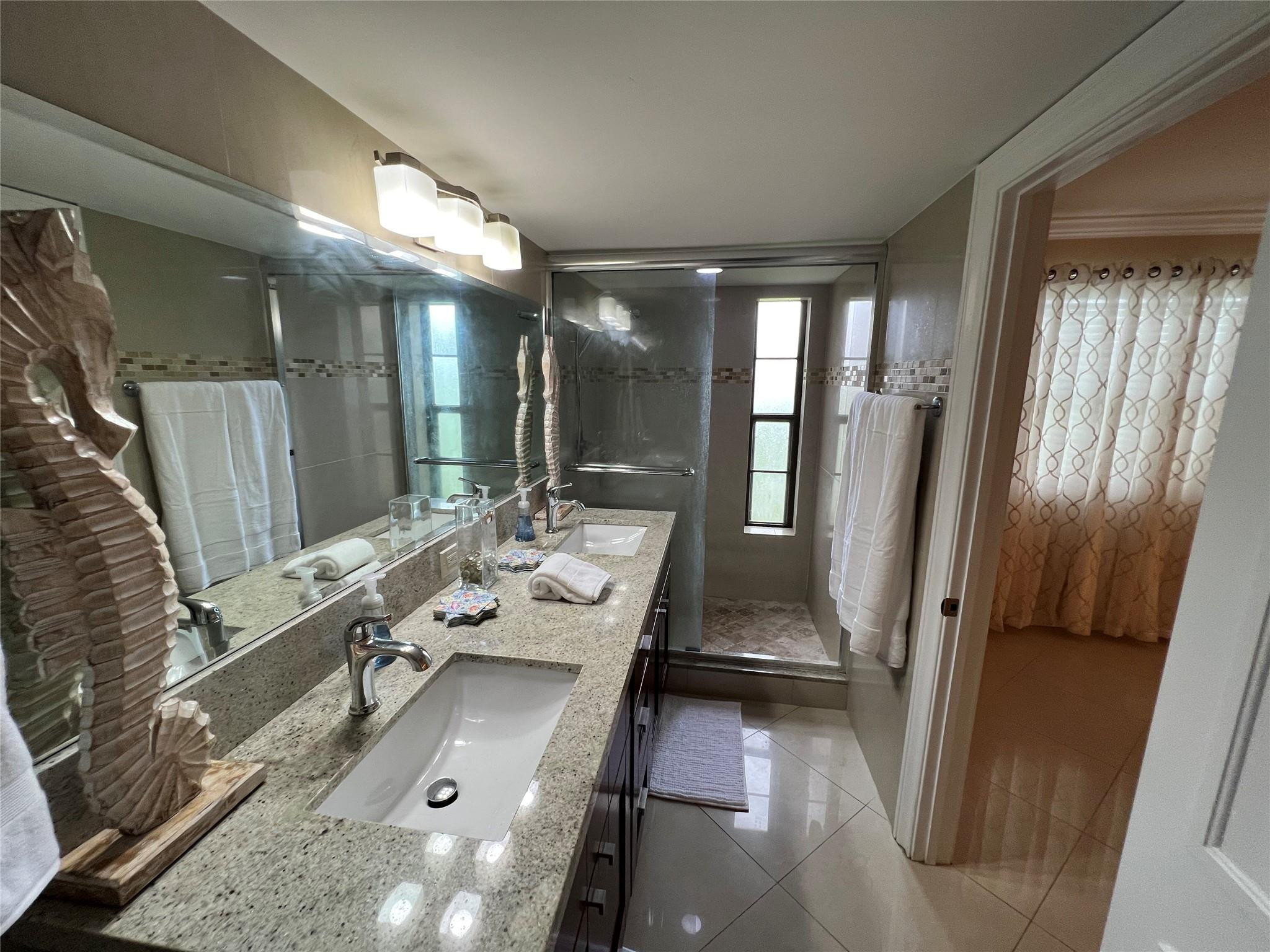 9300 Southwest 8th Street, Unit 108 Boca Raton, FL 33428 - Photo 15 of 40 a bathroom with a tub sink vanity and a mirror