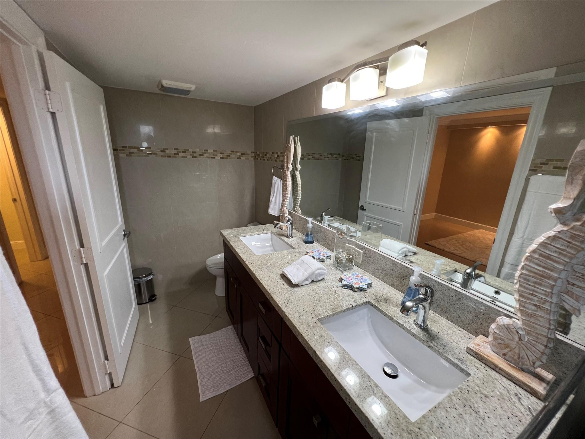 9300 Southwest 8th Street, Unit 108 Boca Raton, FL 33428 - Photo 17 of 40 a bathroom with a double vanity sink a mirror and a shower