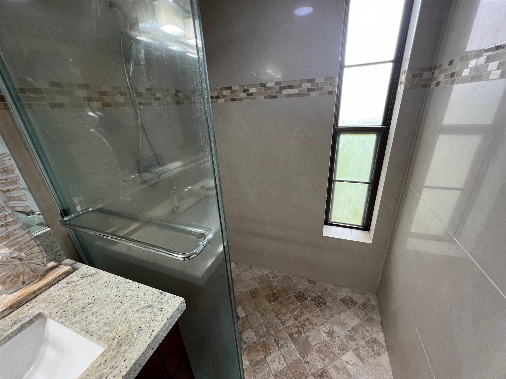 9300 Southwest 8th Street, Unit 108 Boca Raton, FL 33428 - Photo 18 of 40 a bathroom with a granite countertop sink a mirror and shower