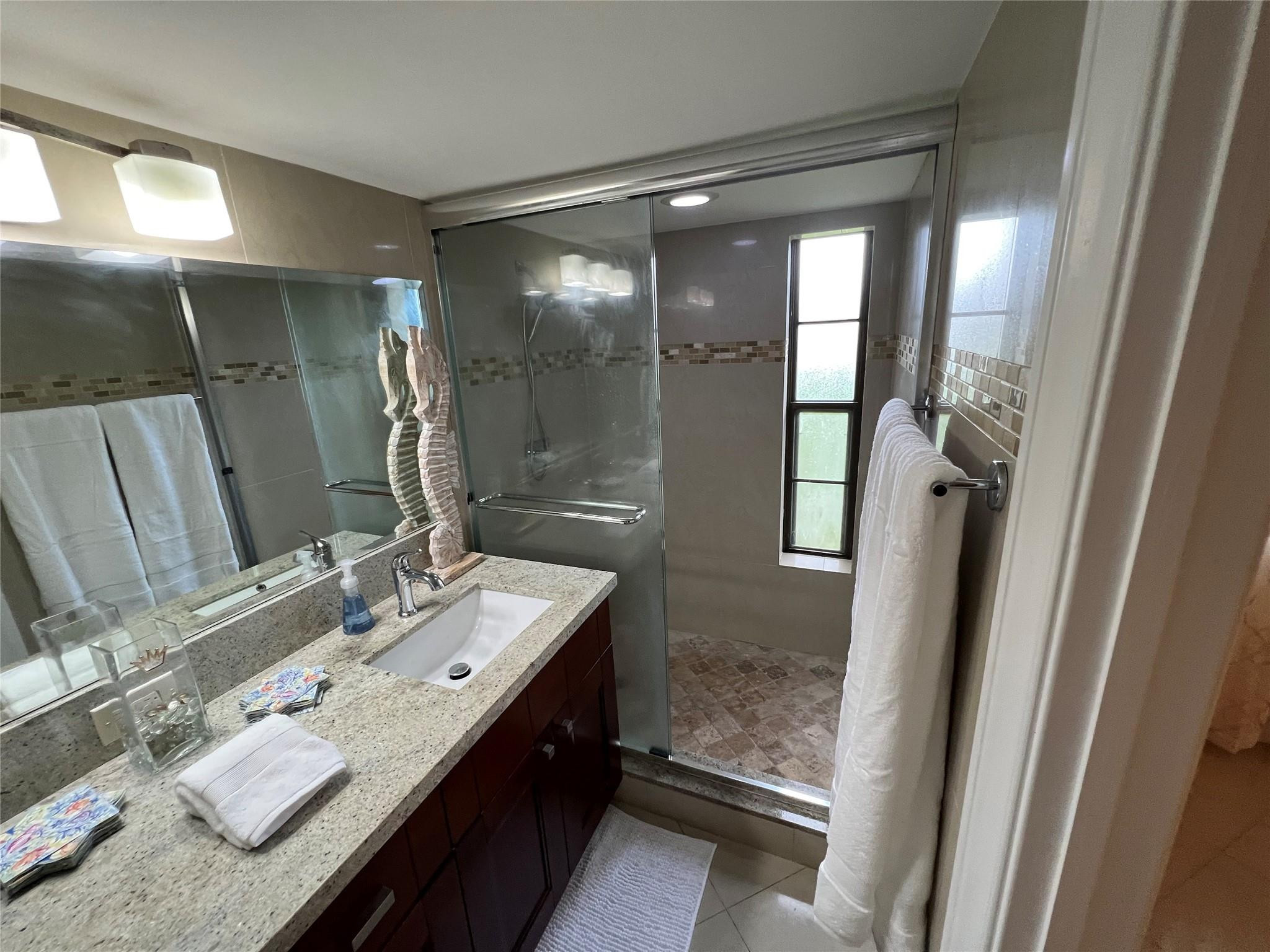 9300 Southwest 8th Street, Unit 108 Boca Raton, FL 33428 - Photo 19 of 40 a bathroom with a double vanity sink mirror and shower