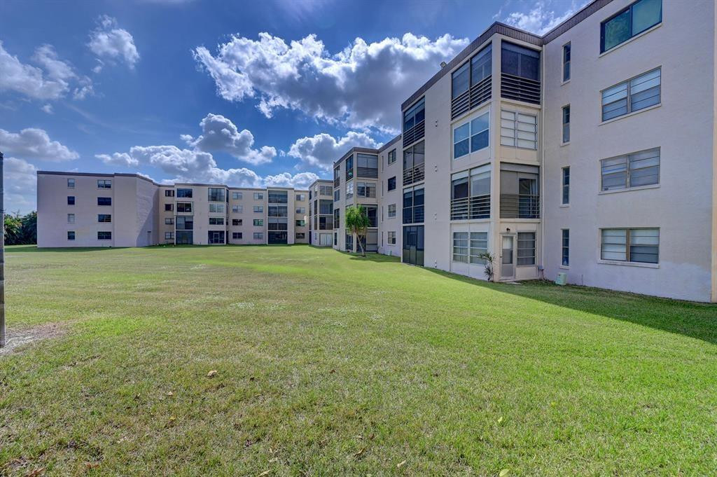 9300 Southwest 8th Street, Unit 108 Boca Raton, FL 33428 - Photo 2 of 40 a view of a house with a big yard and large trees