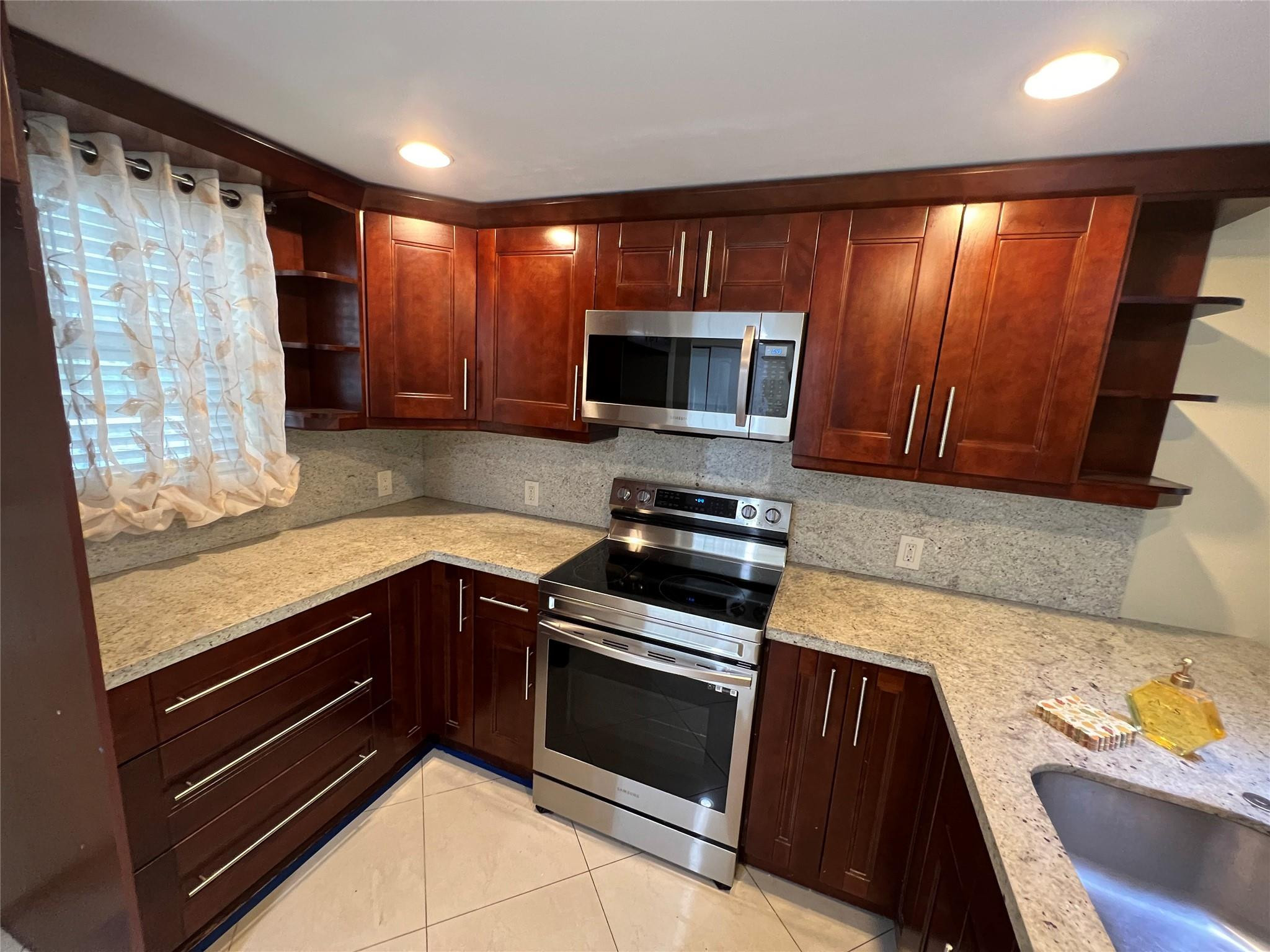 9300 Southwest 8th Street, Unit 108 Boca Raton, FL 33428 - Photo 39 of 40 a kitchen with granite countertop wooden cabinets and stainless steel appliances