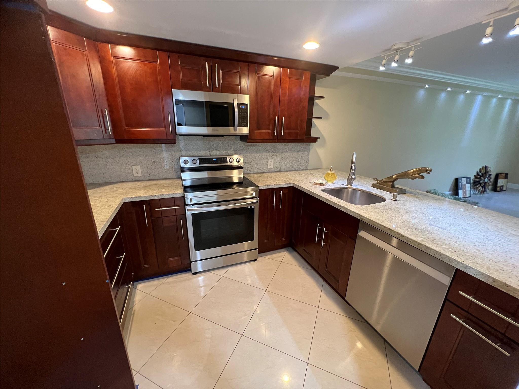 9300 Southwest 8th Street, Unit 108 Boca Raton, FL 33428 - Photo 40 of 40 a kitchen with stainless steel appliances a sink a stove a microwave a sink a refrigerator and grey cabinets
