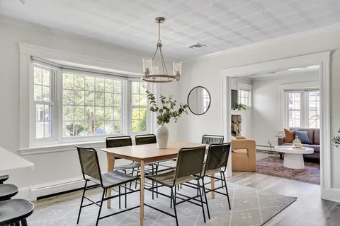 a view of a dining room with furniture a chandelier and wooden floor