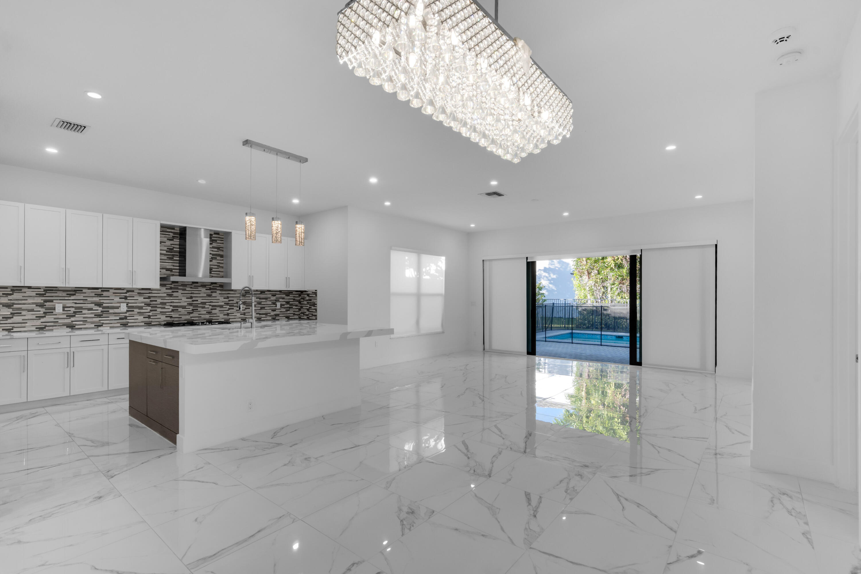 8281 Oceanus Drive Boca Raton, FL 33496 - Photo 48 of 52 a large white kitchen with a white countertops and chandelier