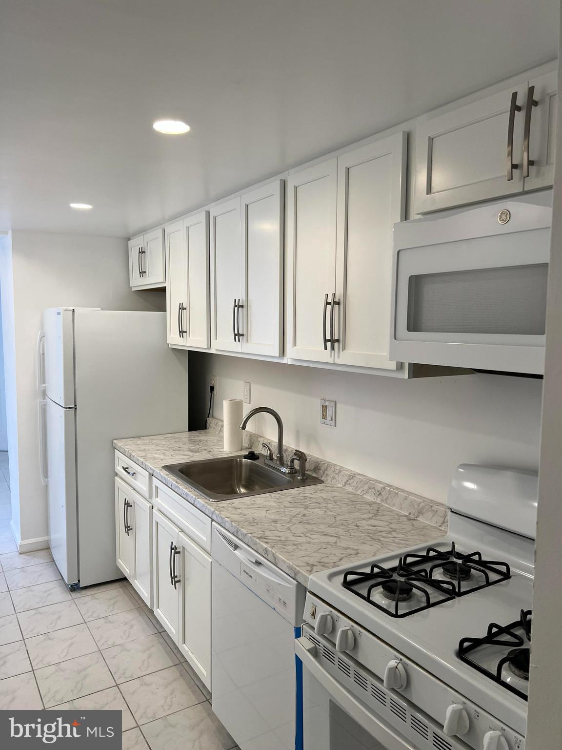 a kitchen with granite countertop stainless steel appliances a sink a stove and cabinets