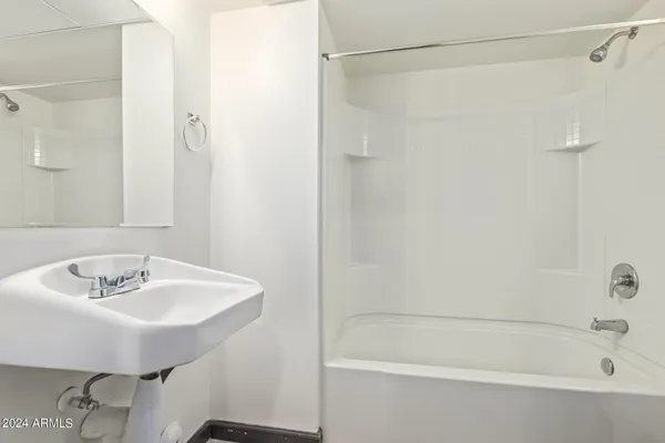 a white bath tub sitting next to a white sink and a shower