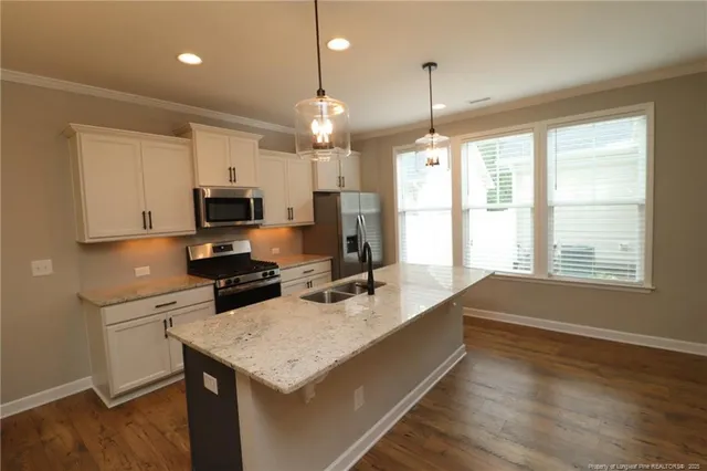 a kitchen that has a lot of cabinets a sink dishwasher and a stove with wooden floor
